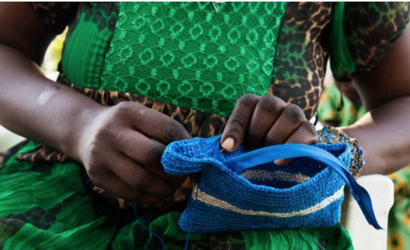 Image of a women from Women's Initiative, The Gambia, making a bag with her hands